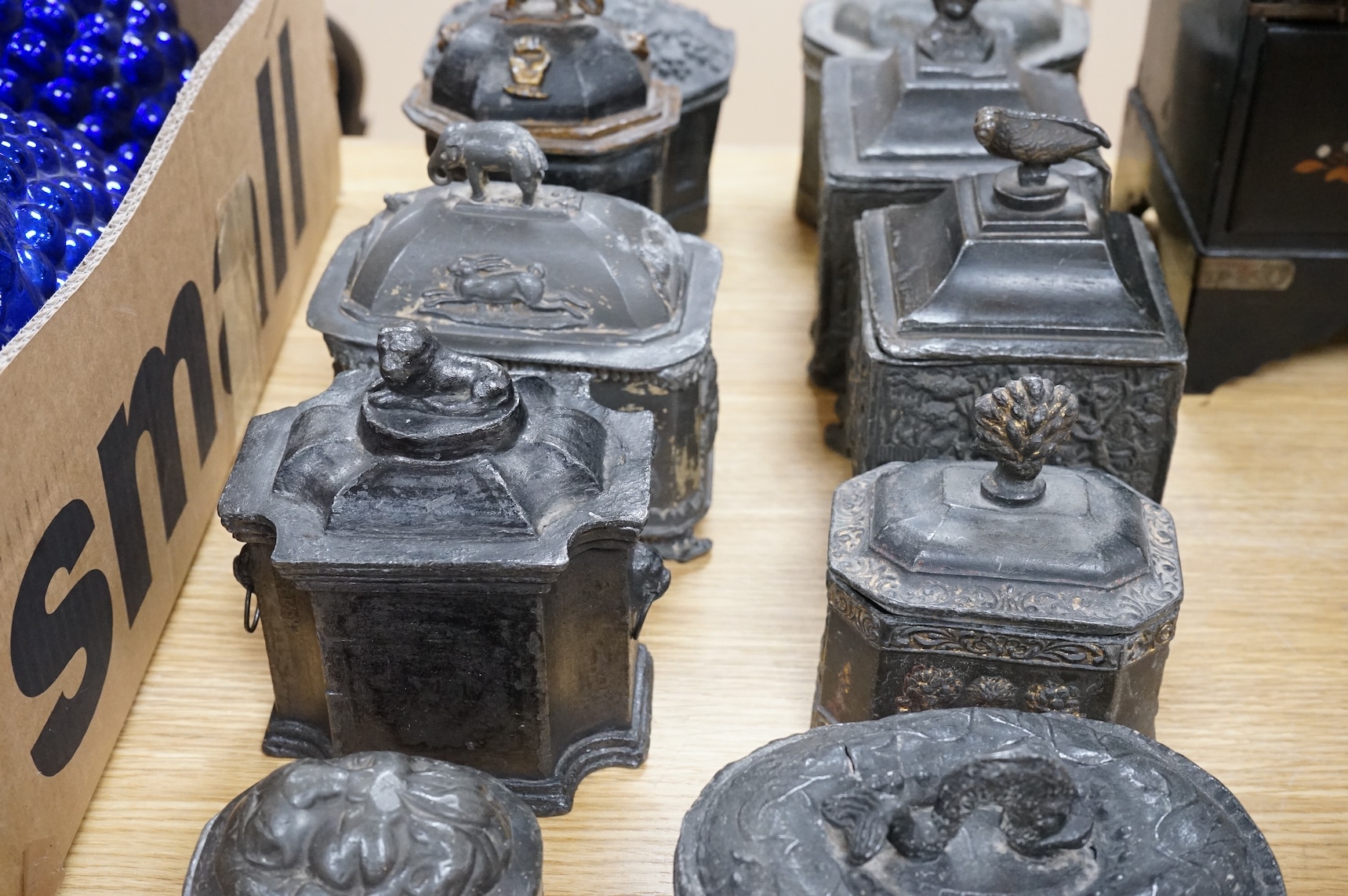 A collection of ten early 19th century lead tobacco boxes, one in the form of a monument with lion knop, largest 14cm wide